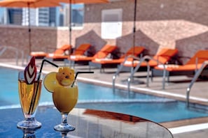 A poolside area with orange lounge chairs and two cocktails on a table. - City Stay Hotel Expo Center Sharjah (Sharjah)