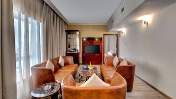A spacious living room with leather sofas, a coffee table, and a flat-screen TV.