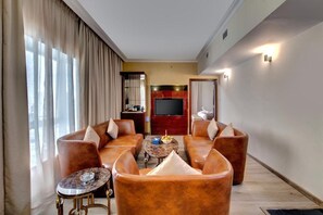 Ein großzügiges Wohnzimmer mit Ledersofas, einem Couchtisch und einem Flachbildfernseher.