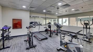 A gym with treadmills, elliptical machines, and weight stations.