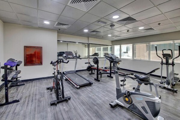 A gym with treadmills, elliptical machines, and weight stations. - City Stay Hotel Expo Center Sharjah (Sharjah)