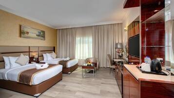 A hotel room with two beds, a desk with a chair, a TV, and a painting on the wall.
