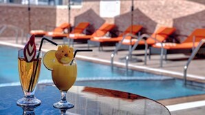 A poolside area with orange lounge chairs and two cocktails on a table. - City Stay Hotel Expo Center Sharjah (Sharjah)