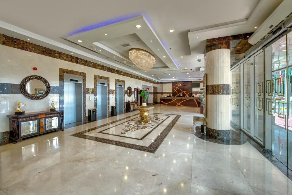 A spacious lobby with a marble floor, a central chandelier, and a reception desk.