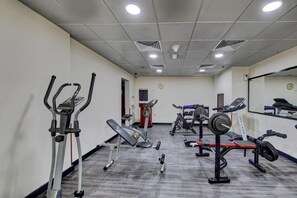 Une salle de sport équipée de divers appareils d’exercice, notamment des tapis de course, des vélos elliptiques et des bancs de musculation.