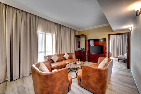 A living room with leather sofas, a coffee table, and a flat-screen TV. - City Stay Hotel Expo Center Sharjah (Sharjah)