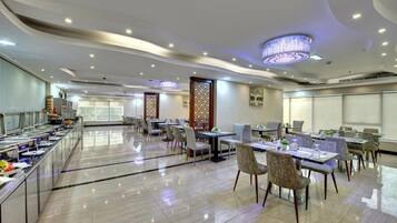 A spacious dining area with multiple tables and chairs, a buffet line, and decorative wall panels.