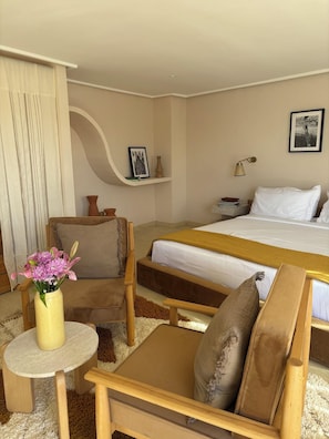 A hotel room with a bed, two chairs, a small table, a nightstand, and a picture on the wall. - Zen Zone Boutique Riad & Spa (Marrakech)