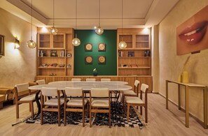 A modern meeting room with a round table, chairs, wooden bookshelves, and decorative wall art. - Zen Zone Boutique Riad & Spa (Marrakech)