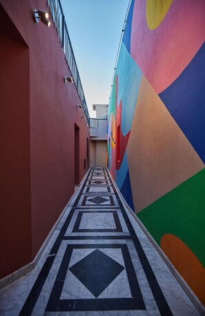 A corridor with a geometric patterned floor, a colorful wall mural, and a metal railing on the left. - Zen Zone Boutique Riad & Spa (Marrakech)
