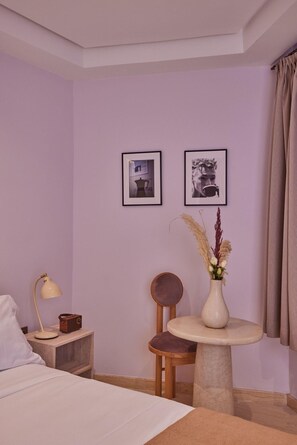 A hotel room with a bed, a small table with a vase of flowers, a chair, a lamp, and two framed pictures on the wall. - Zen Zone Boutique Riad & Spa (Marrakech)