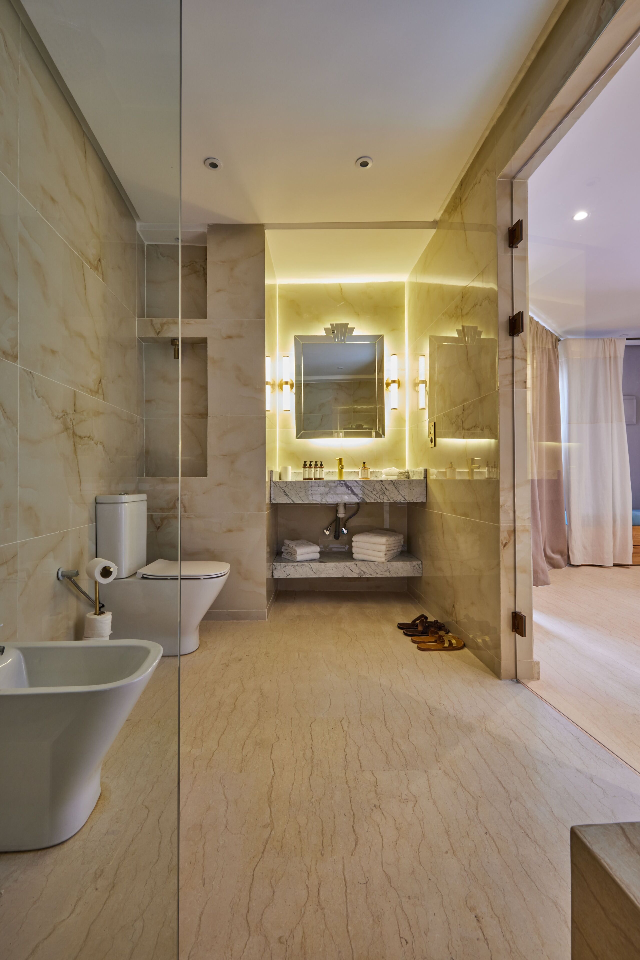 A modern bathroom with a freestanding bathtub, a toilet, and a sink with a marble countertop.