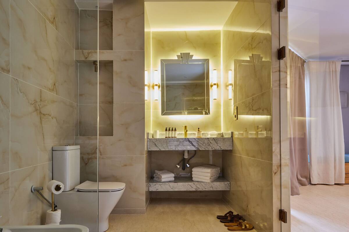 A modern bathroom with a freestanding bathtub, a toilet, and a sink with a marble countertop.