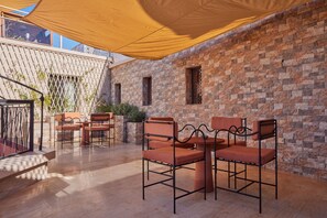 An outdoor patio with a brick wall, a table with chairs, and a canopy. - Zen Zone Boutique Riad & Spa (Marrakech)