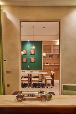 A modern interior with a dining area, a green accent wall, and a wooden bookshelf. - Zen Zone Boutique Riad & Spa (Marrakech)