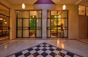 A hotel lobby with a checkered floor, large glass doors leading to rooms, and pendant lighting. - Zen Zone Boutique Riad & Spa (Marrakech)