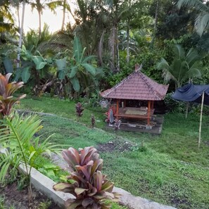A small gazebo with a tiled roof, surrounded by lush greenery and banana plants. - Indrayoga Retreat Bali (Selemadeg)