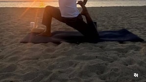 Une personne effectuant une posture de yoga sur une plage au coucher du soleil.