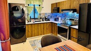 Een compacte keuken met houten kastjes, een ingebouwde oven, een magnetron en een wasmachine.