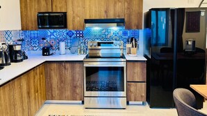 Een moderne keuken met houten kasten, een roestvrijstalen fornuis, een magnetron en een koelkast.