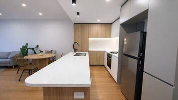 A modern kitchen with a central island, built-in appliances, and a dining area with wicker chairs.