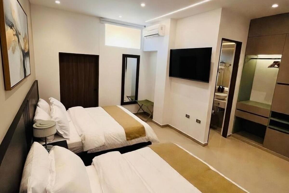 Ein Hotelzimmer mit einem großen Bett, einem Flachbildfernseher, einer Klimaanlage und einer kleinen Sitzecke.