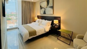 Une chambre d’hôtel moderne, équipée d’un lit, d’une chaise, d’une petite table et d’un tableau au mur.