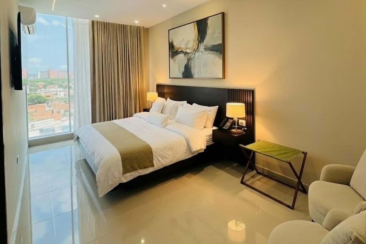 Ein modernes Hotelzimmer mit Bett, Stuhl, kleinem Tisch und einem Bild an der Wand.