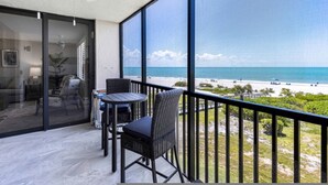 A balcony with a view of the beach, a table, and chairs. - 3rd-floor Corner Unit w Gulf Views Heated Pool (Sanibel)