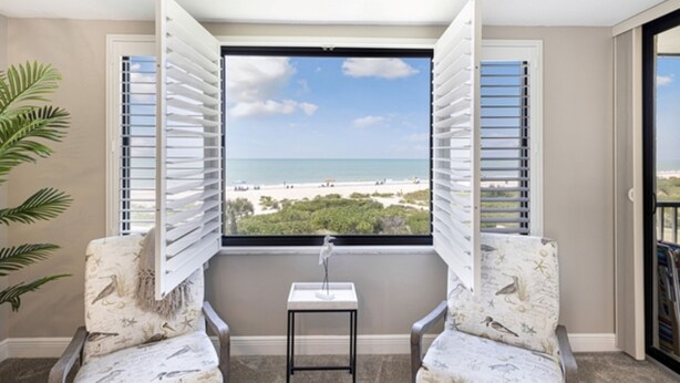 A balcony with a view of the beach, two chairs, a small table, and a potted plant. - 3rd-floor Corner Unit w Gulf Views Heated Pool (Sanibel)
