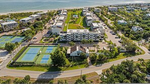 A coastal resort with multiple buildings, a tennis court, and a beach in the background. - 3rd-floor Corner Unit w Gulf Views Heated Pool (Sanibel)