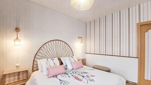 Ein Schlafzimmer mit einem Bett, zwei Wandleuchten, einer Pendelleuchte und einer Wandverkleidung mit Streifen.