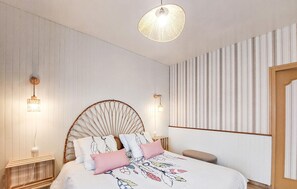 Ein Schlafzimmer mit einem Bett, zwei Wandleuchten, einer Pendelleuchte und einer Wandverkleidung mit Streifen.