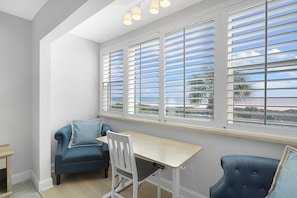 A room with a desk, two chairs, a window with blinds, and a view of the outdoors. - Oceanfront 2BD/2BA w/Parking, Wi-Fi, Work Space, Beach Access & Community Pool (St. Augustine)