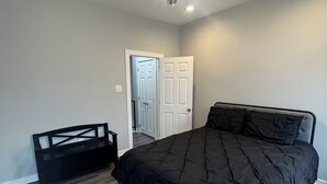 Ein Schlafzimmer mit einem Bett, einem Deckenventilator, einer Tür und einer Bank.