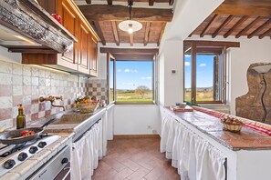 A kitchen with a stove, a sink, and a window overlooking a landscape. - Casale Le Sorgenti - Farmhouse with Pool for 8, Pitigliano, Italy (Pitigliano)