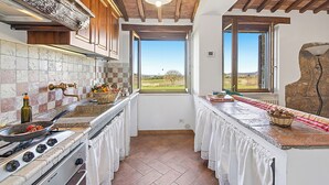 A kitchen with a stove, oven, and a view through an open window. - Casale Le Sorgenti - Farmhouse with Pool for 8, Pitigliano, Italy (Pitigliano)