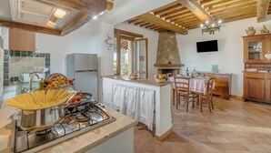 A kitchen with a stove, a sink, and a dining area with chairs and a table. - Casale Le Sorgenti - Farmhouse with Pool for 8, Pitigliano, Italy (Pitigliano)