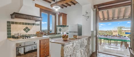 A kitchen with a stone island, wooden beams, and a view of the outdoors.