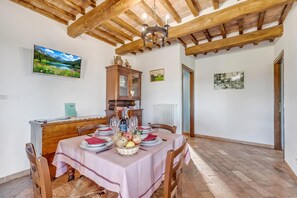 Un coin repas avec une table dressée pour quatre personnes, un buffet en bois, un téléviseur et des œuvres d’art accrochées aux murs.