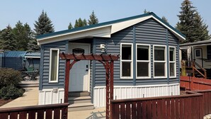 Ein kleines, eingeschossiges Haus mit Veranda und Holzlattenzaun.