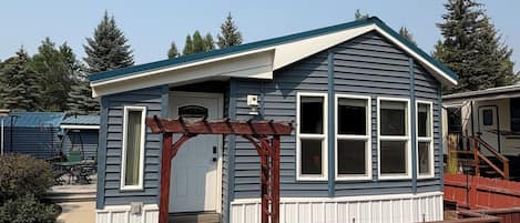 Une petite maison de plain-pied avec une véranda et une clôture en bois.