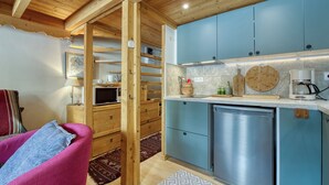 Une cuisine de taille réduite avec des meubles bleus, un lave-vaisselle encastré et un plafond en bois.