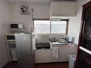 Una cocina compacta con refrigerador, microondas, lavaplatos y armarios.