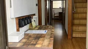 Un pasillo estrecho con una mesa de madera, un armario blanco y una escalera.