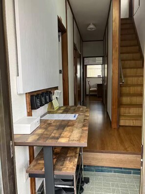 Un pasillo estrecho con una mesa de madera, un armario blanco y una escalera.