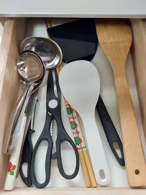 A drawer containing kitchen utensils including a spoon, spatula, and scissors. - Rinkukan (Izumisano)