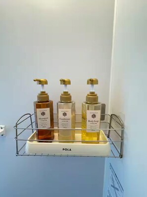A bathroom shelf with three bottles of shampoo, conditioner, and body soap. - Rinkukan (Izumisano)