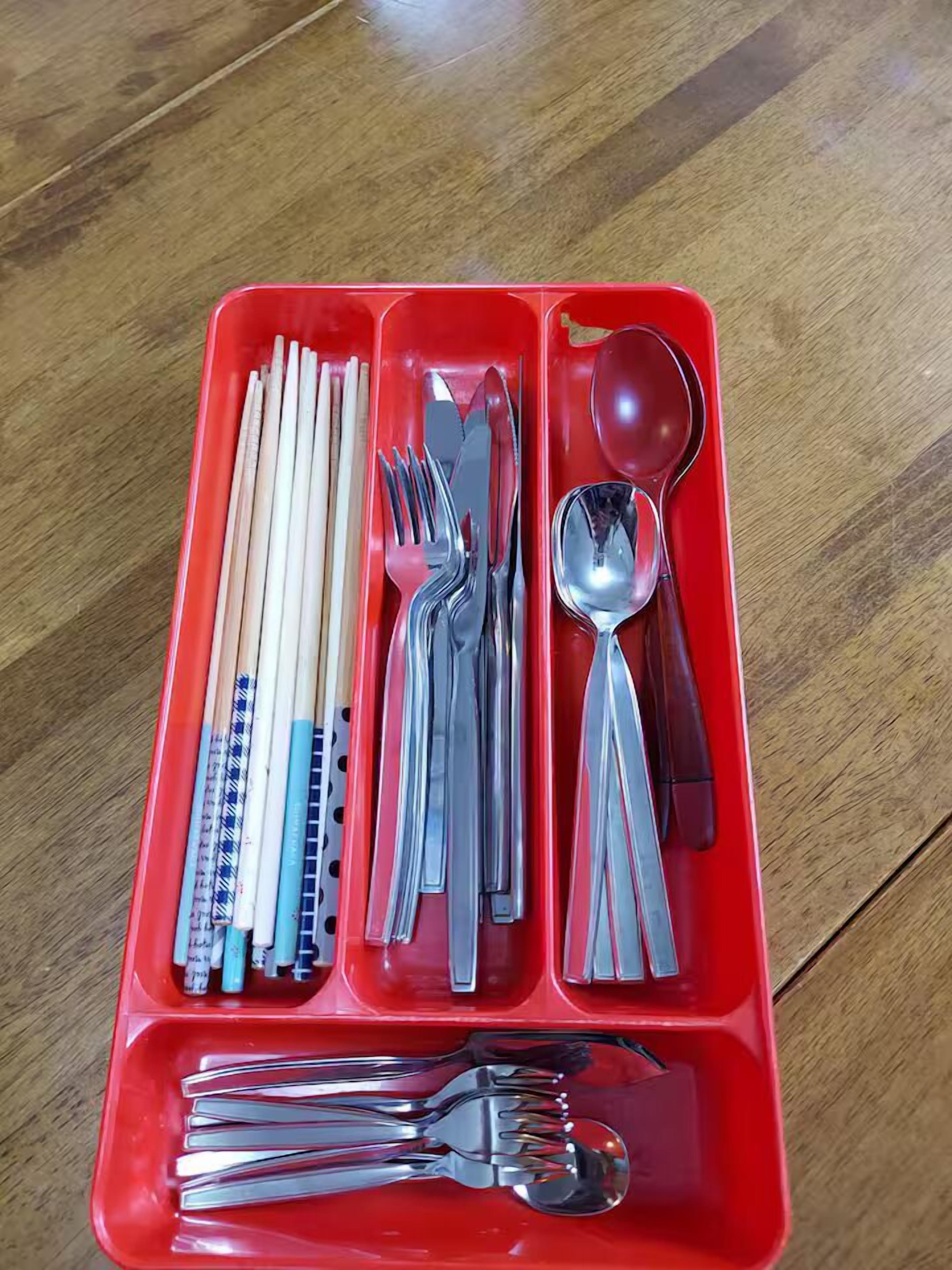 A red tray with chopsticks, forks, spoons, and knives.