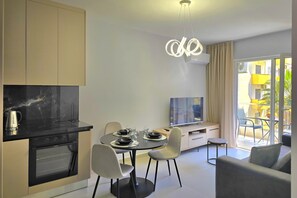 Una cocina moderna con zona de comedor, sofá y televisor.